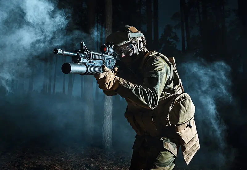 A cowboy shot of a military personnel holding a rifle